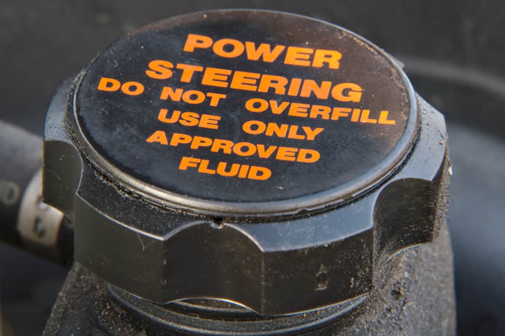 Power steering hydraulic oil cap in black with orange text